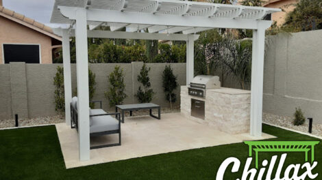 Modern outdoor patio with seating and built-in grill under pergola.