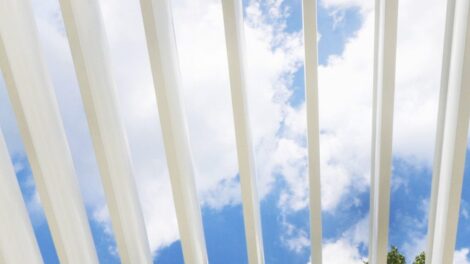 View of blue sky and clouds through white vertical slats.
