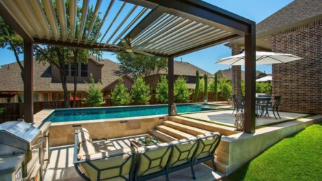 Modern backyard with pool and shaded seating area under pergola.